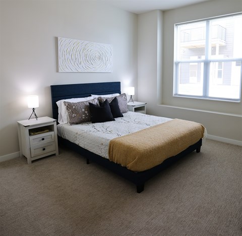 Furnished bedroom with upholstered bed and nightstands at The Daniels 1 and 2 Apartments, Saukville, WI