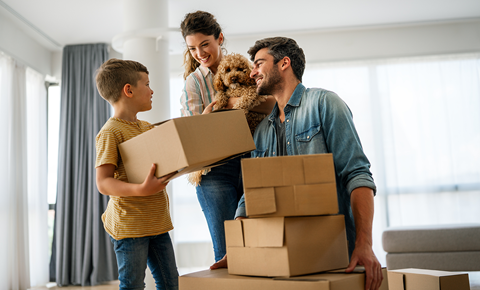 A family is moving into a new home with boxes and a dog.