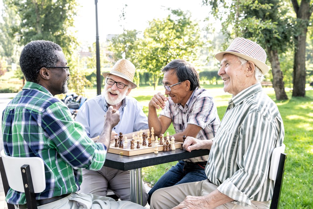 Four men playing chess in a park.