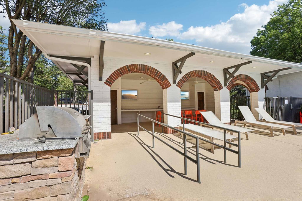 A building with a white roof and arched openings has a concrete wall in front of it.
