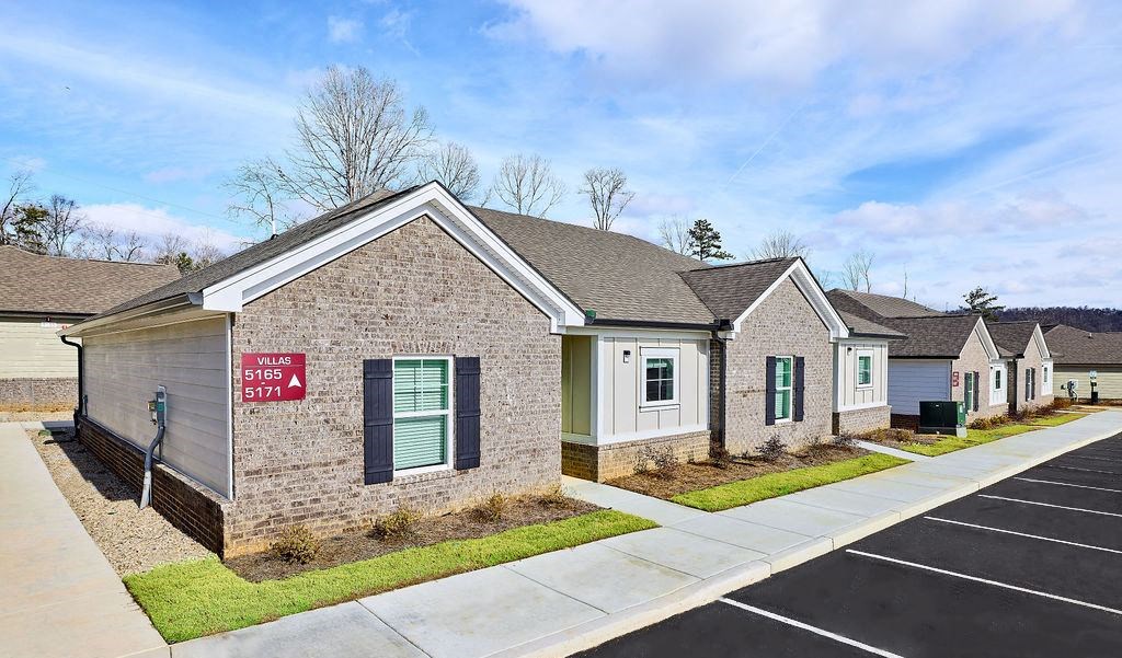 a brick house with green shutters and a sidewalk