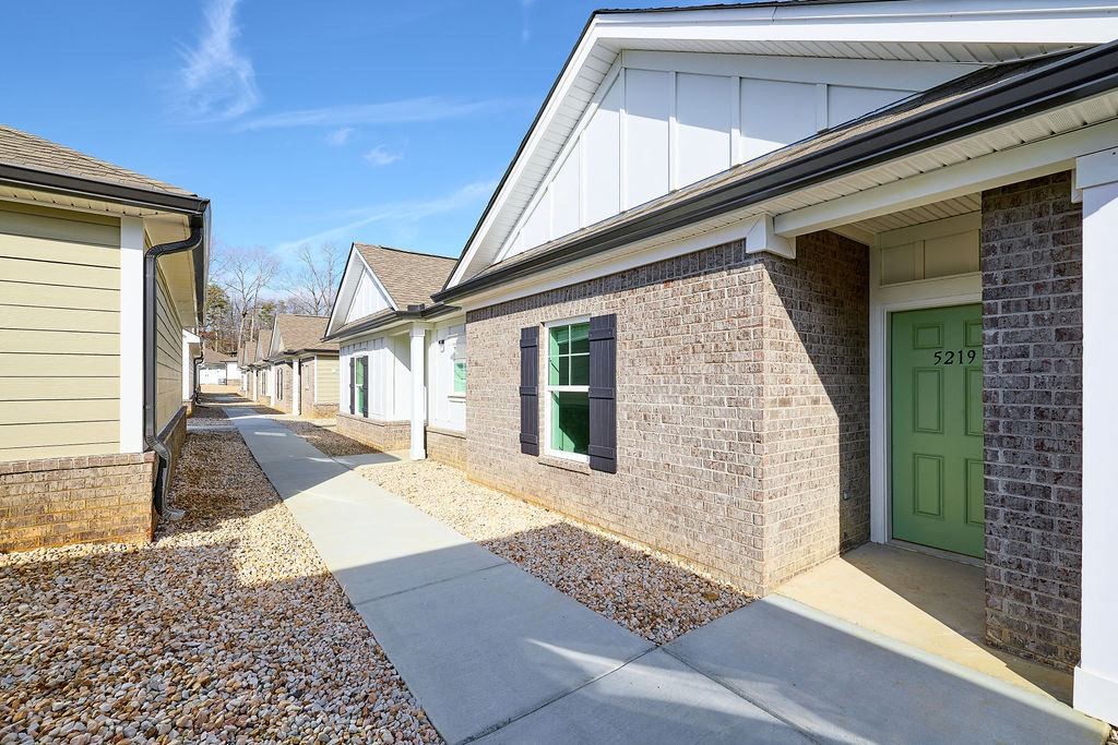 a sidewalk in front of a house with a green door