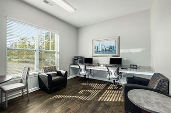 A room with a desk, chairs, and a painting on the wall.