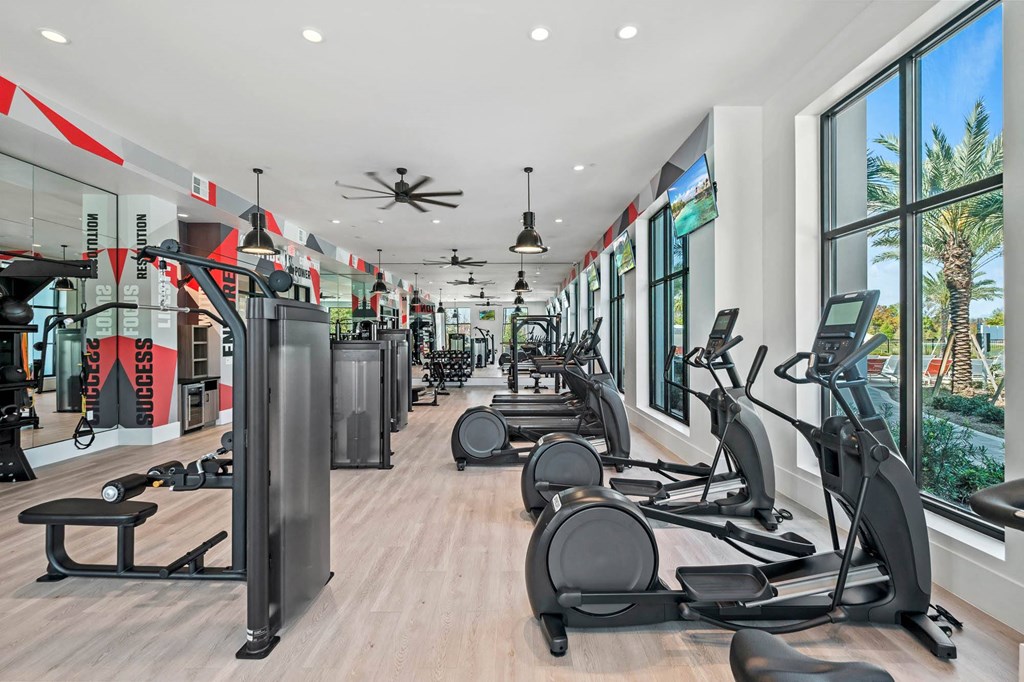 a gym with cardio equipment and windows in a building