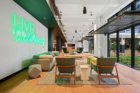 a living room filled with furniture and a large green neon sign