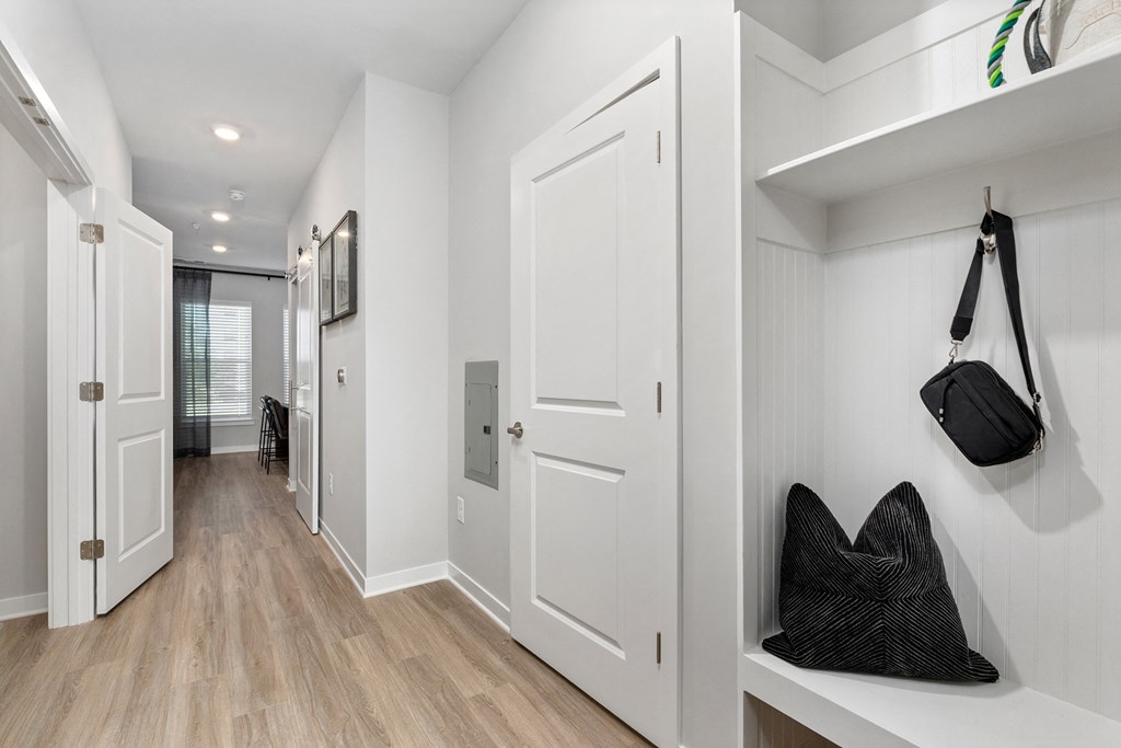 A hallway with a bench and a purse hanging on the wall.