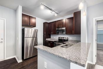 A kitchen with a granite countertop and stainless steel appliances.