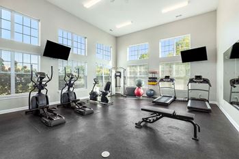 A spacious gym with a variety of equipment including treadmills, exercise bikes, and a bench press.