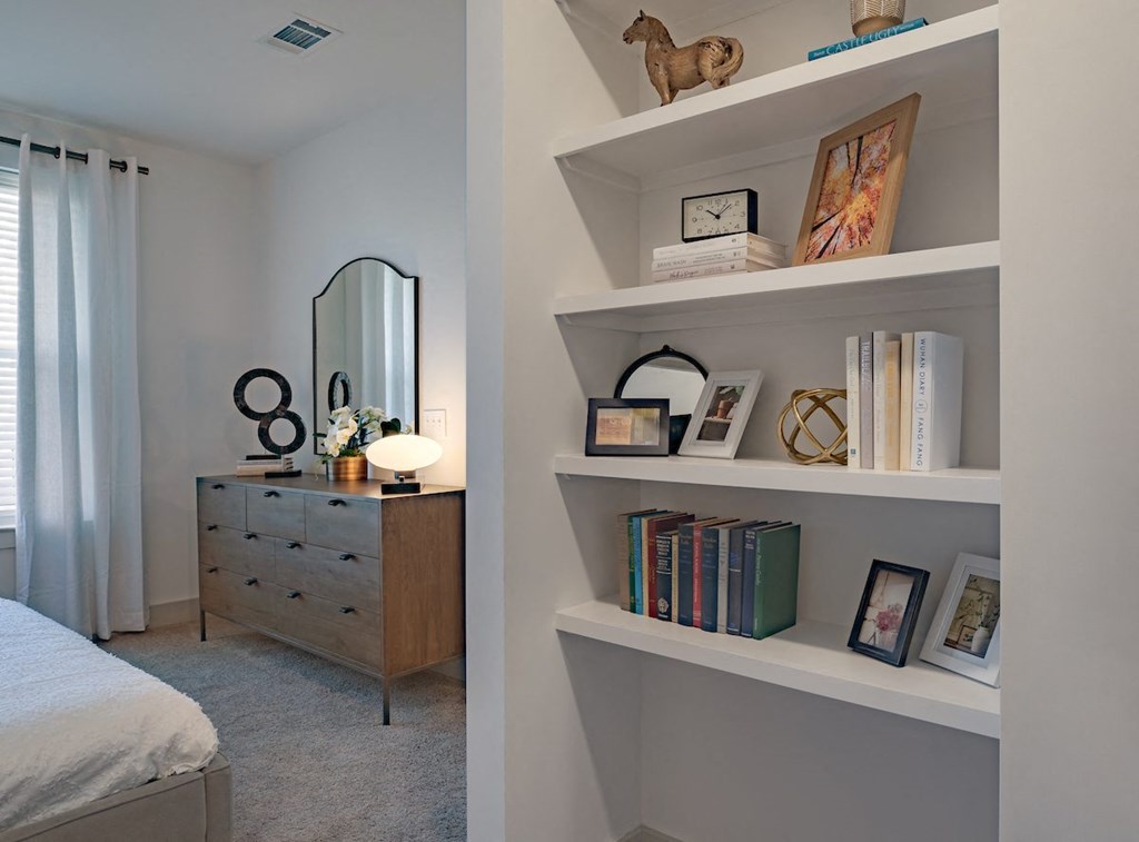 a bedroom with white shelves and a bed and a dresser