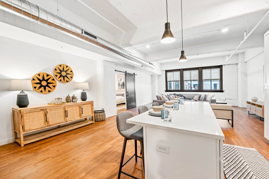 a kitchen and living room with white walls and hardwood floors