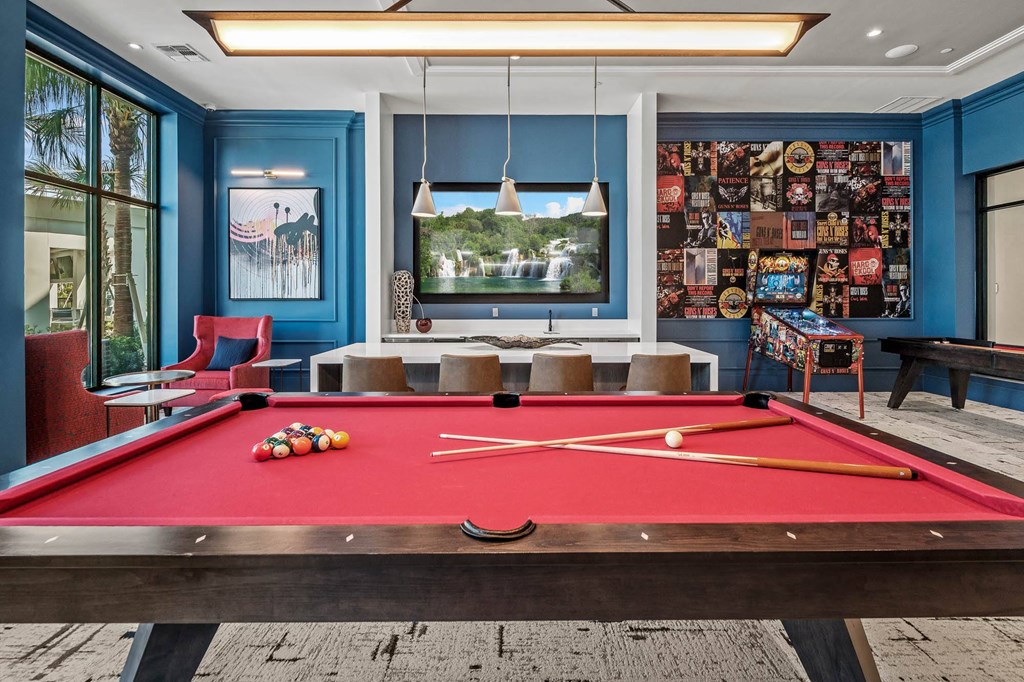 a pool table in a living room with a bar and a television