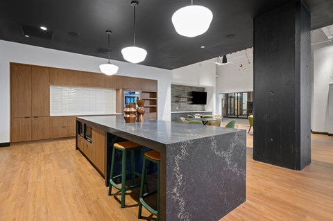 a kitchen with a large island with stools and a living room in the background