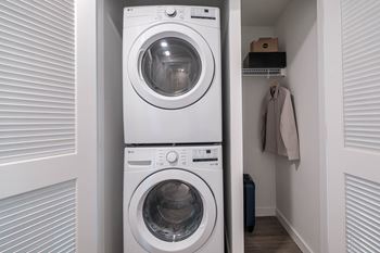 A white washing machine is in a small laundry room at Altis Santa Barbara, Florida