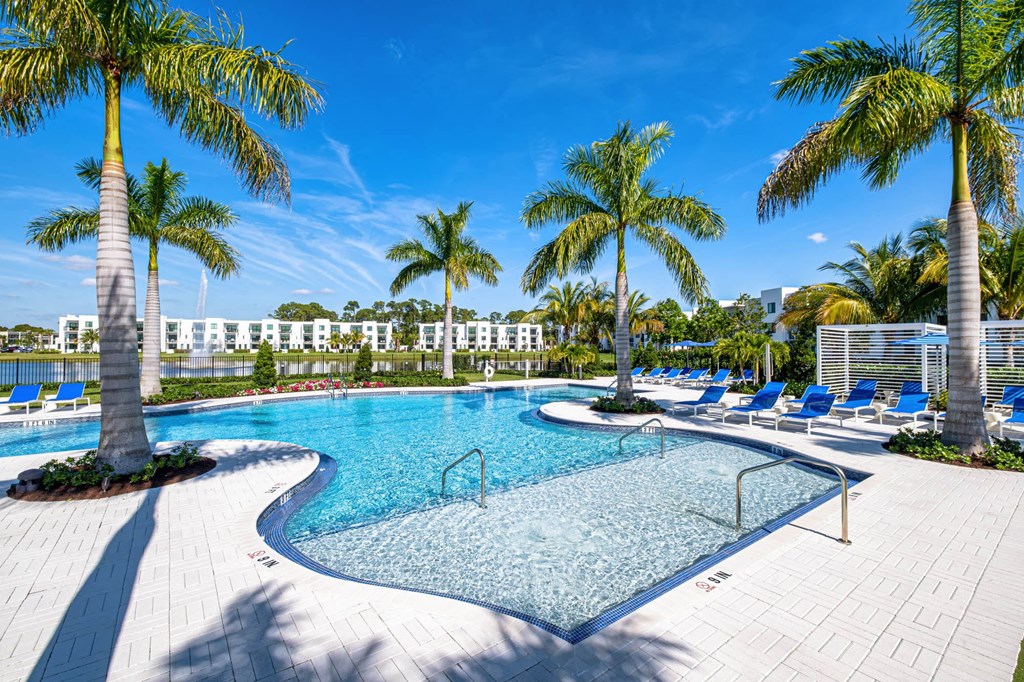 A swimming pool surrounded by palm trees and lounge chairs. at Altis Blue Lake, Lake Worth, 33467