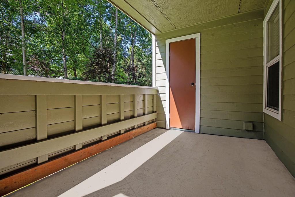 a balcony with a door and trees in the background
