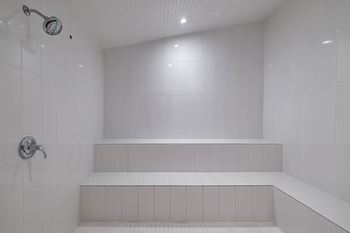 a white bathroom with a shower and white tiles  at Altis Grand Suncoast Apartments, Florida
