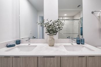 A bathroom with two sinks and a vase of flowers on the counter at Altis Santa Barbara, Florida