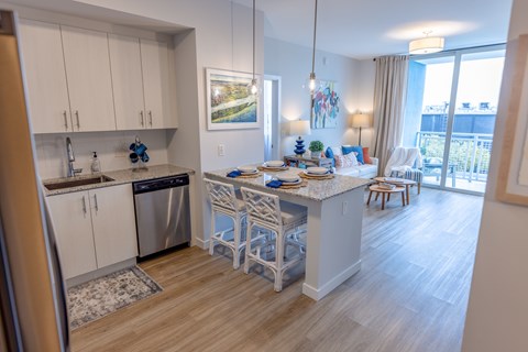 A kitchen with a dining table set for two with a view of the balcony.