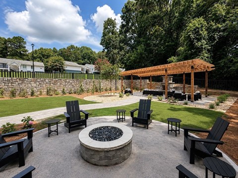 A backyard with a fire pit and chairs.