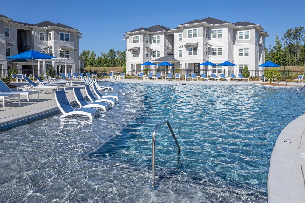 a large pool with blue chairs and a building in the background