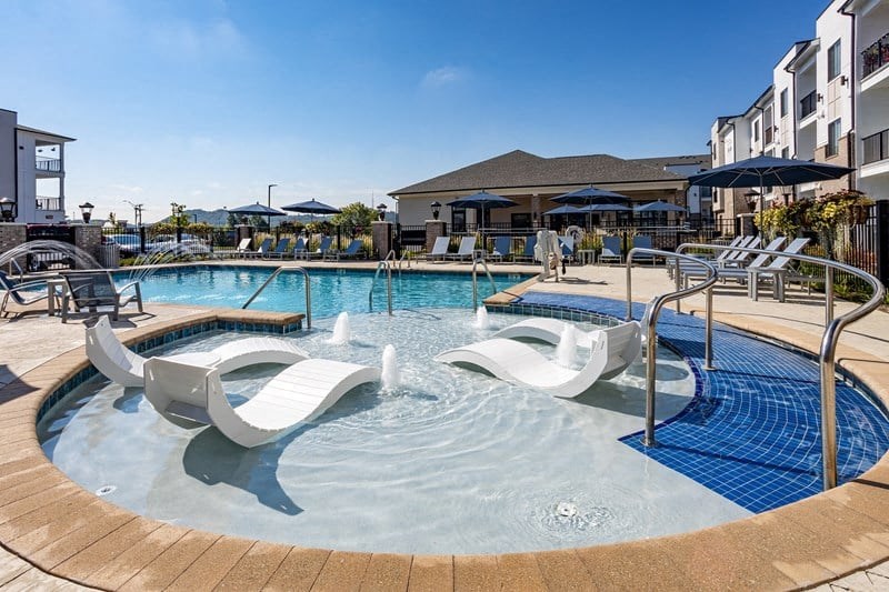a resort style swimming pool with white chaise lounge chairs
