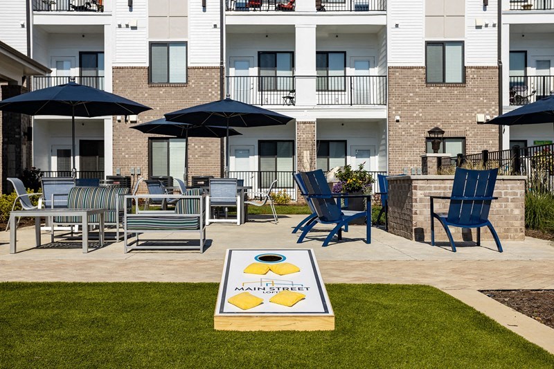 an outdoor patio with blue chairs and umbrellas at an apartment complex