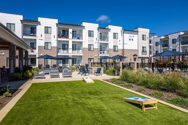 an exterior view of an apartment building with a lawn and a fire pit