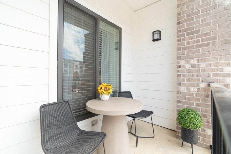 a small patio with two chairs and a table and a window