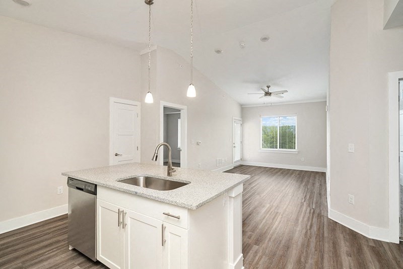 an empty kitchen and living room with white cabinets and a sink