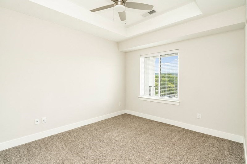 an empty living room with a ceiling fan and a window
