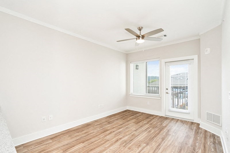 an empty living room with a ceiling fan and a window