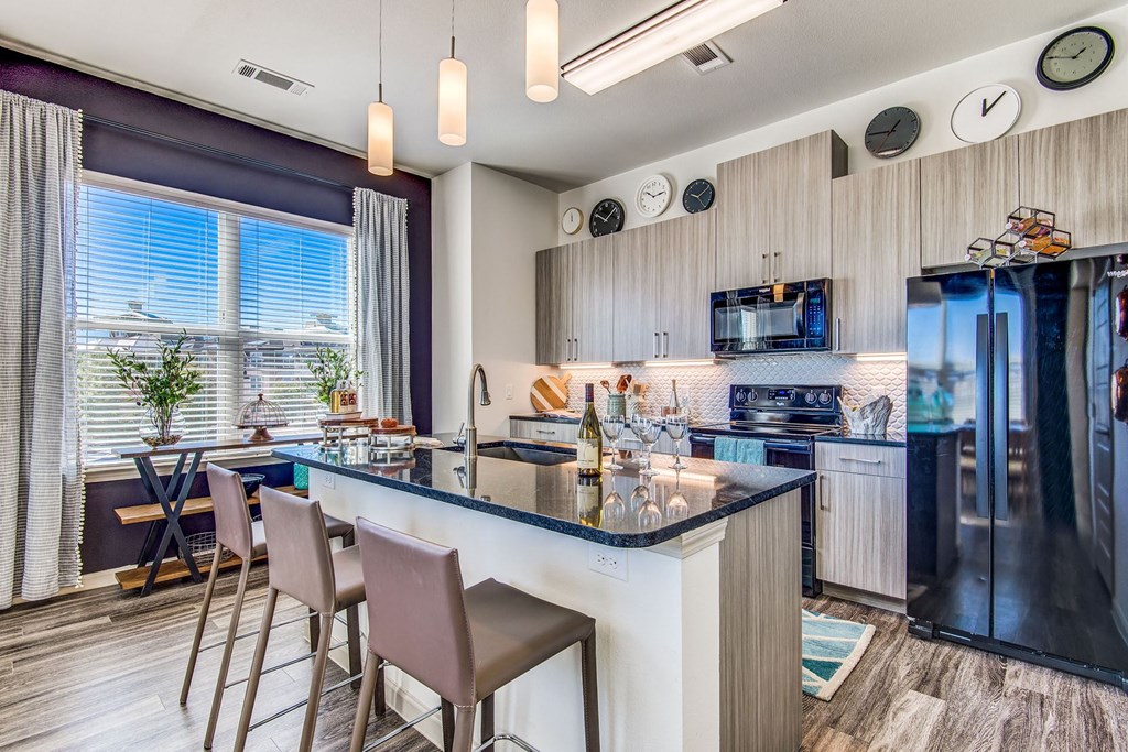 Two Bedroom Apartments in Lewisville, TX - Hebron 121 Station - Modern Kitchen with Large Island, Stainless Steel Appliances, and Granite-Style Countertops.