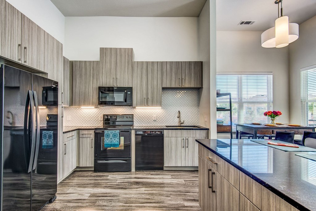 One-Bedroom Apartments In Lewisville, TX - Hebron 121 Station - Open-Concept Kitchen With Granite Countertops, Shaker Style Wood Cabinetry, and Wood-Style Flooring