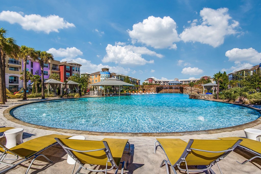 Apartments in Lewisville TX- Exterior Image of Hebron 121 Station's Expansive Pool with Yellow Chaise Chairs, Cabanas, and Gazebo