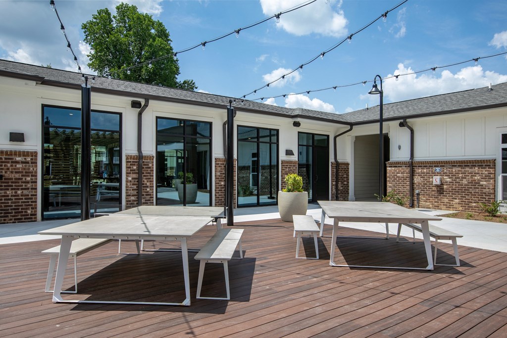 a patio with two white picnic tables and two white benches
