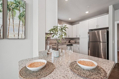 A kitchen with a table topped with bowls of cereal and a potted plant.