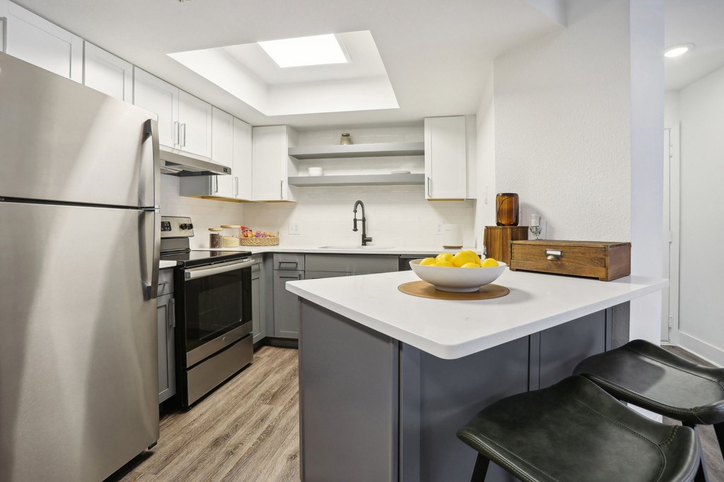A modern kitchen with a refrigerator, oven, and sink.