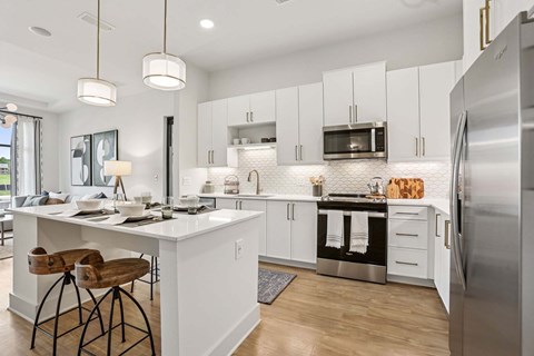 A modern kitchen with white cabinets and a wooden bar stool.