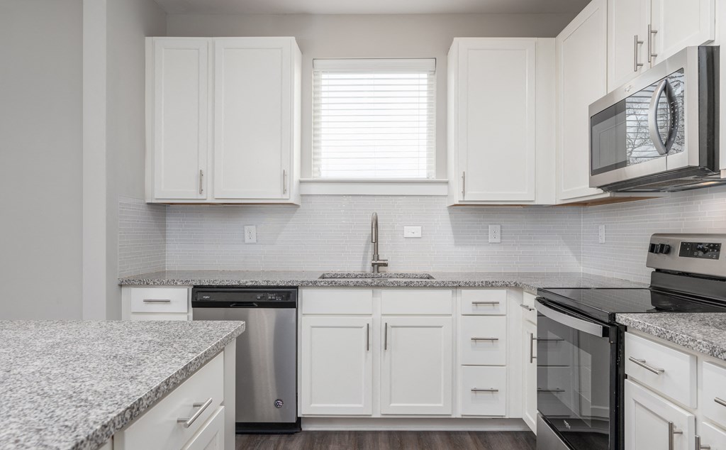 A kitchen with white cabinets and a granite countertop.