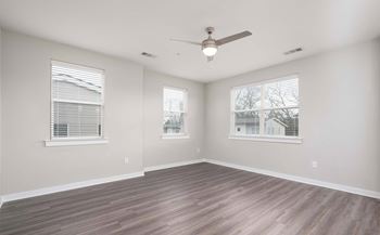 A room with a ceiling fan and two windows.