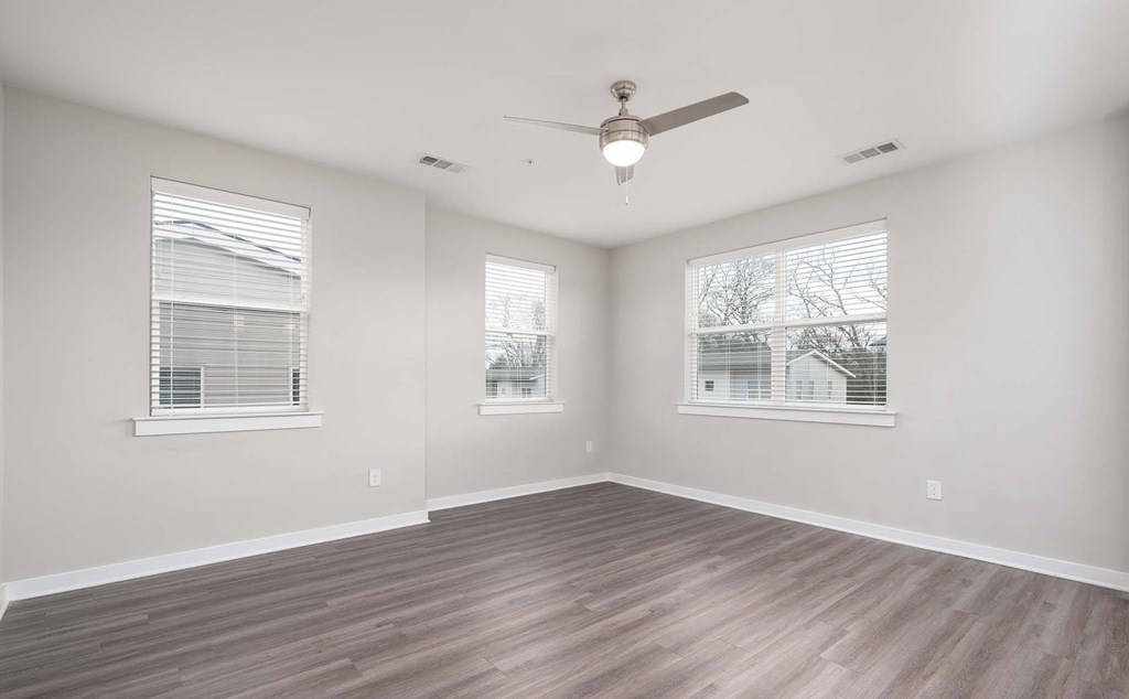A room with a ceiling fan and two windows.