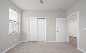 A room with a ceiling fan and three white doors.