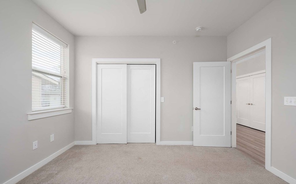 A room with a ceiling fan and three white doors.
