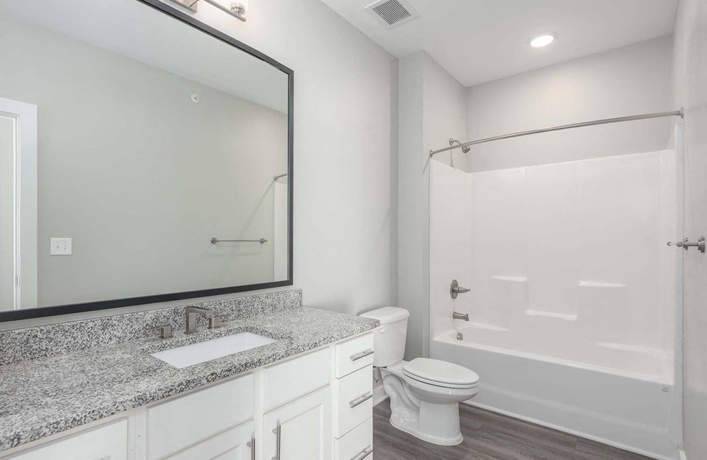 A white bathroom with a toilet, sink, and mirror.