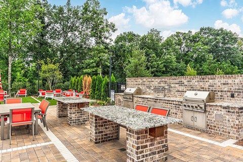a patio with a barbecue grill and tables and chairs
