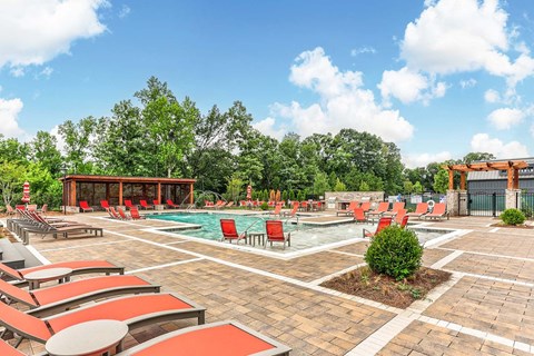a resort style pool with red chairs and umbrellas