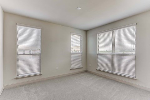 the living room of an empty home with three windows