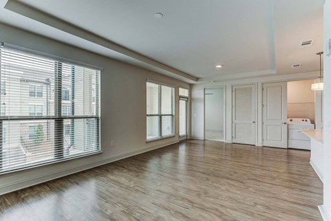 an empty living room with a large window and wood flooring