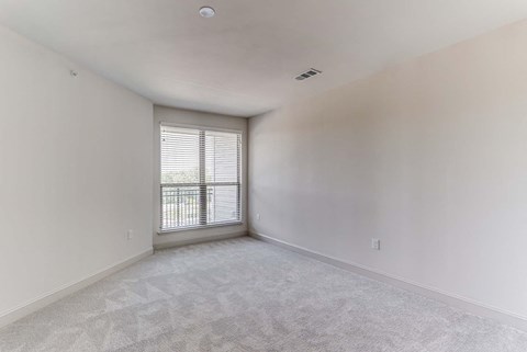 an empty living room with a window and white walls