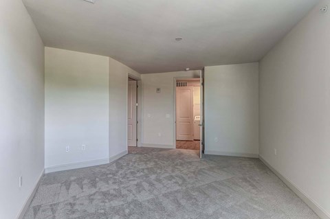 an empty living room with white walls and carpet